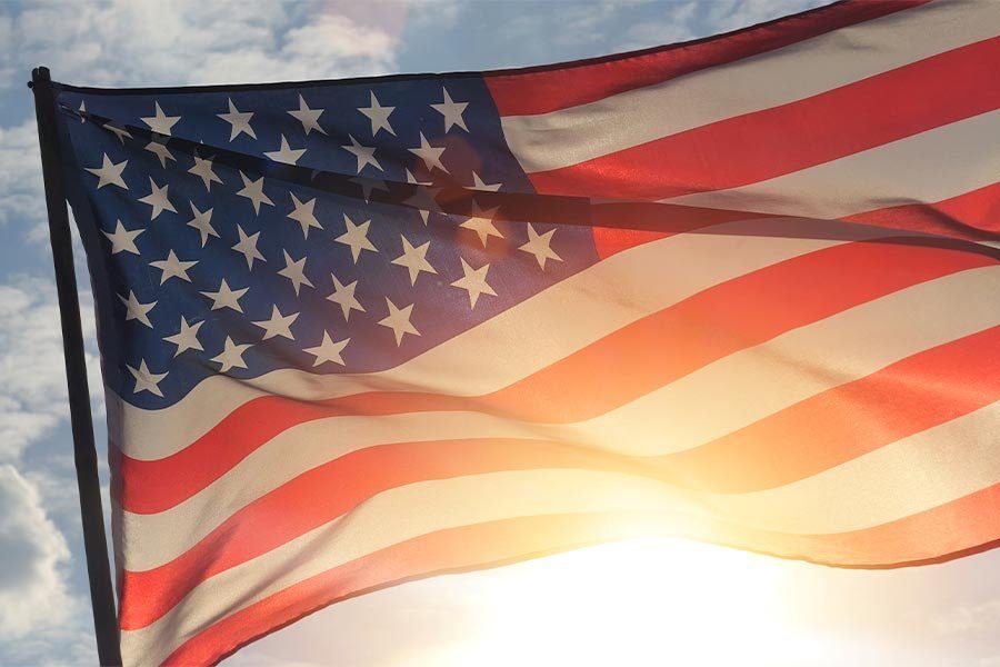 An American flag waving against a sunlit sky