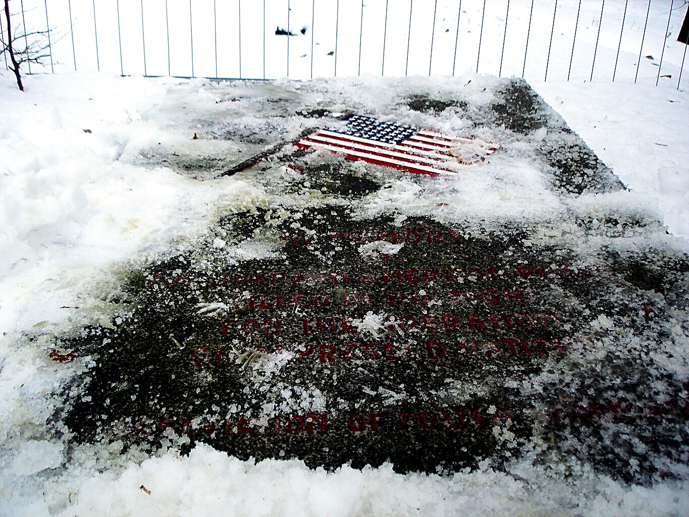 A snow-covered memorial stone bearing a painted American flag, in the Valley of Death at the former Flossenbürg Concentration Camp